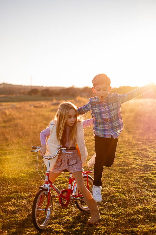 Niño y niña compartiendo bici al atardecer en el campo Madrid