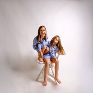 fotografia infantil en estudio dos hermanas sentadas fondo claro madrid