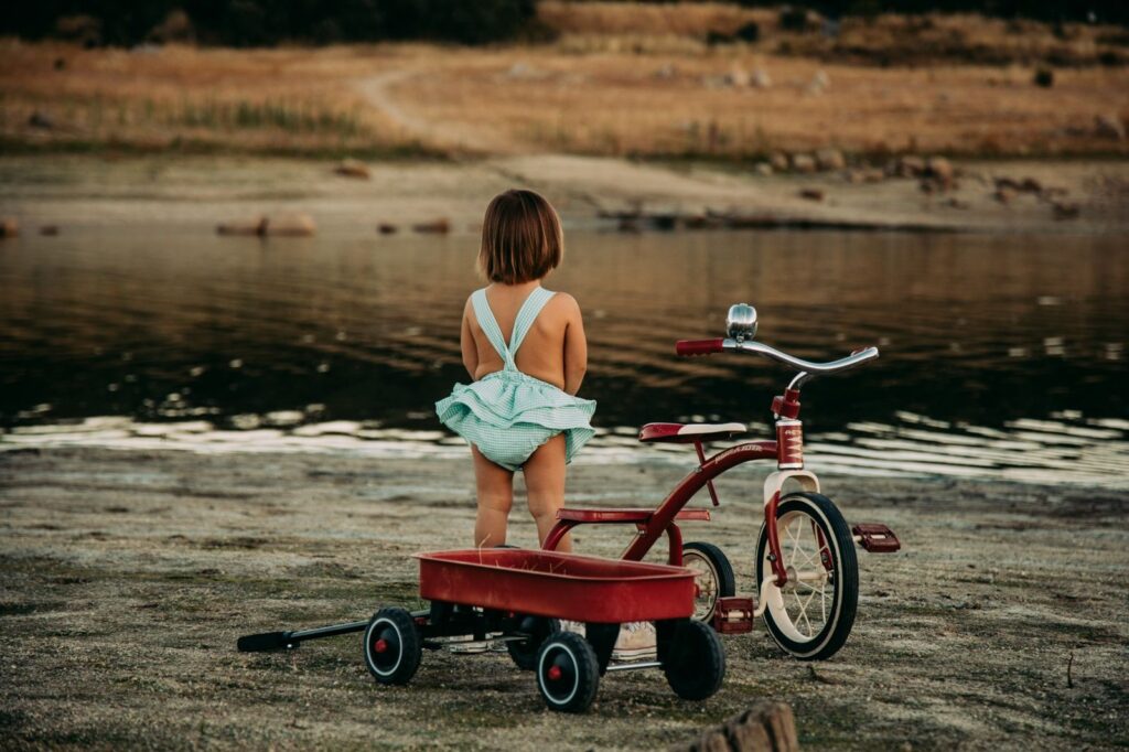 niño jugando con carrito rojo en el campo en sesión infantil en exterior en Madrid Rubén Mejías En el Campito