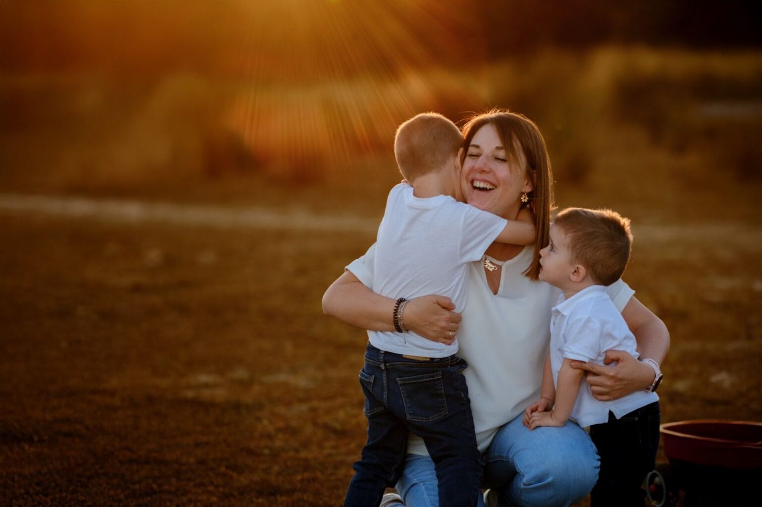 Madre con sus dos hijos abrazados al atardecer en una sesión de fotos familiar en Madrid