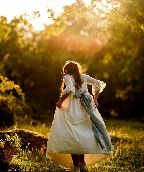 Fotografia de comunion diferente en el campo, niña caminando al atardecer